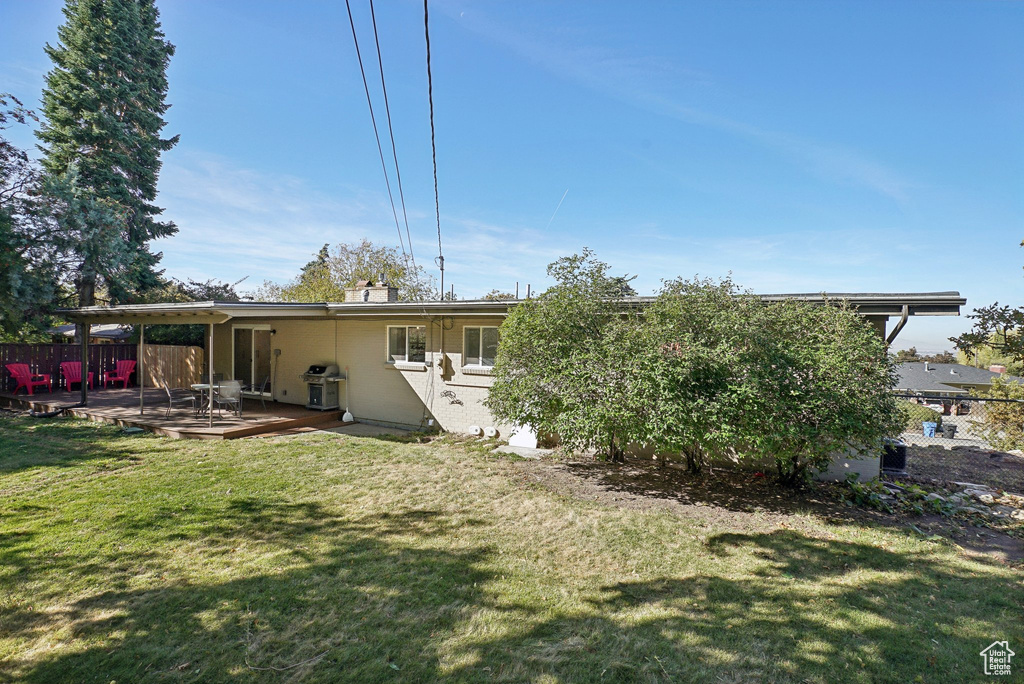 Rear view of house featuring a patio area, a deck, and a lawn