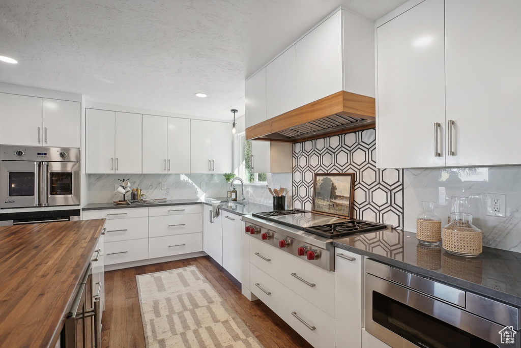 Kitchen with appliances with stainless steel finishes, wood counters, white cabinets, and dark hardwood / wood-style floors