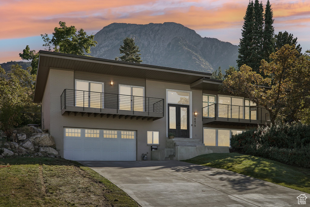 View of front of home with a balcony, a garage, and a mountain view