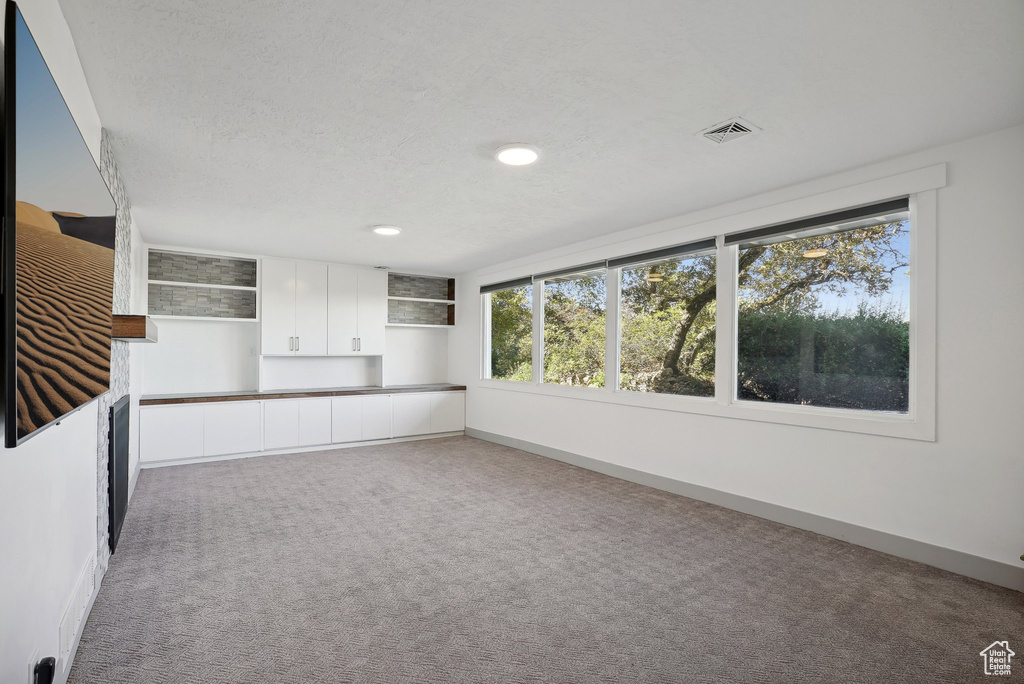 Unfurnished living room with carpet floors and a textured ceiling