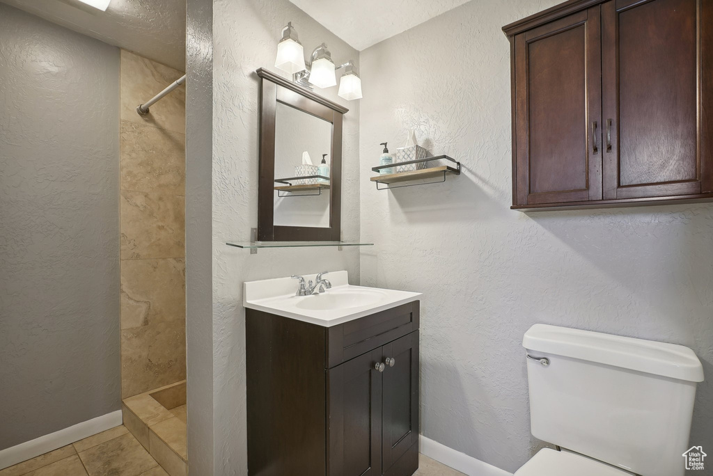 Bathroom with vanity, tile patterned floors, toilet, and walk in shower