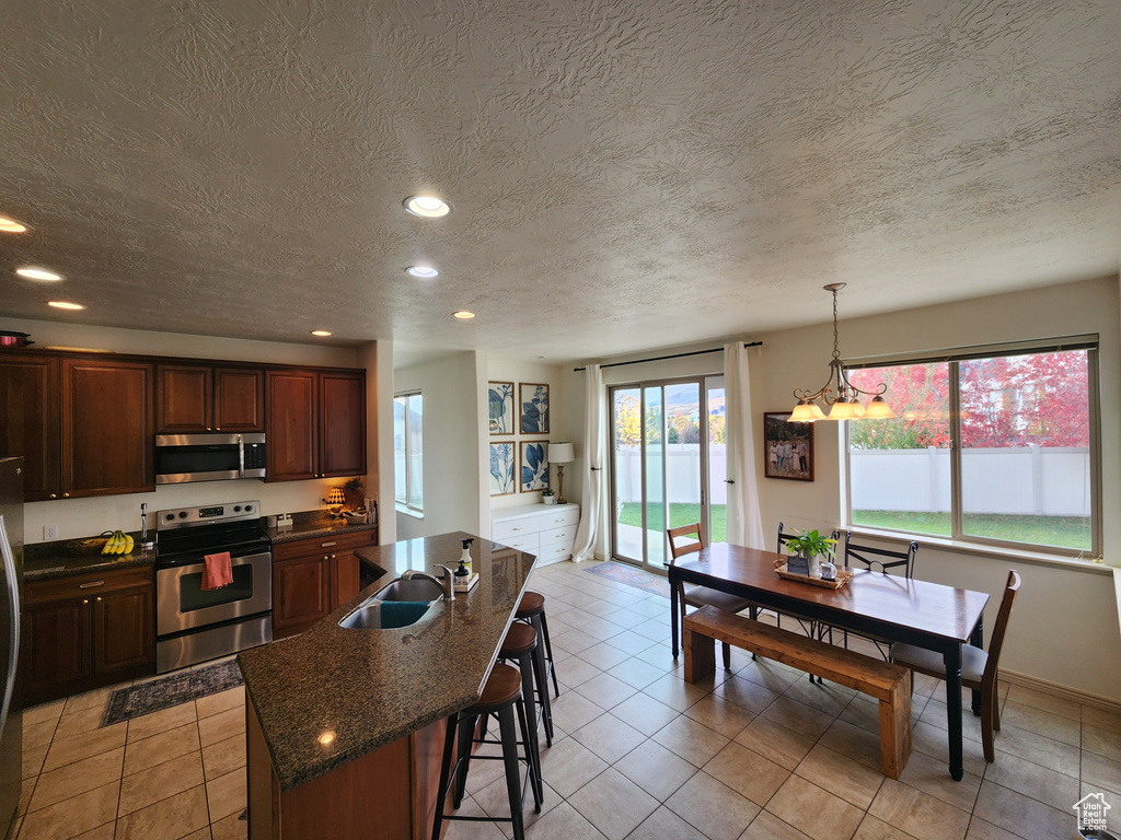 Kitchen featuring a textured ceiling, a kitchen island with sink, sink, and appliances with stainless steel finishes