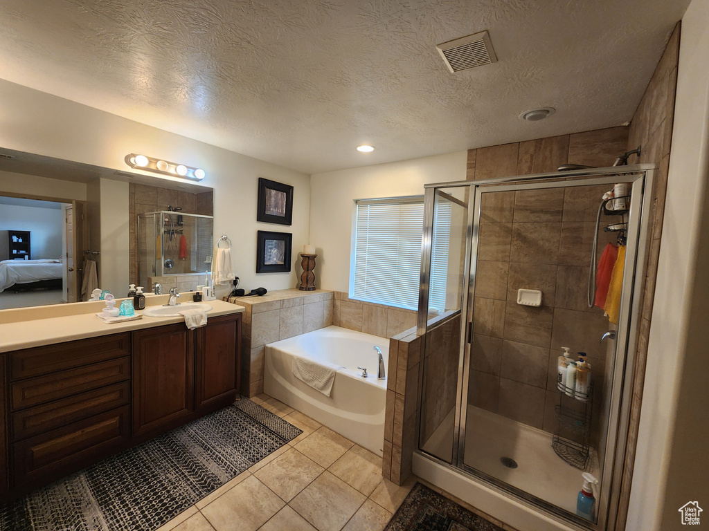 Bathroom with plus walk in shower, tile patterned flooring, vanity, and a textured ceiling