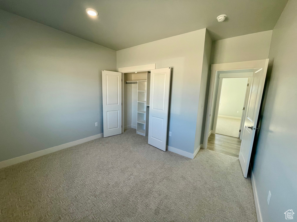 Unfurnished bedroom with light colored carpet and a closet