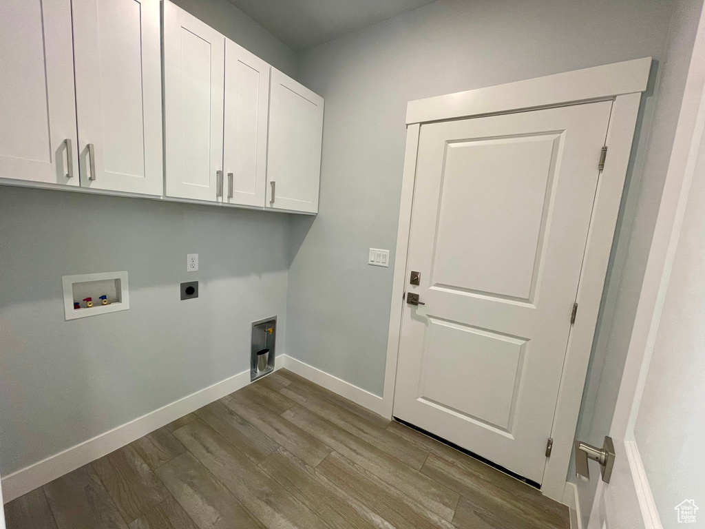 Laundry room featuring hookup for an electric dryer, hookup for a washing machine, light hardwood / wood-style floors, and cabinets