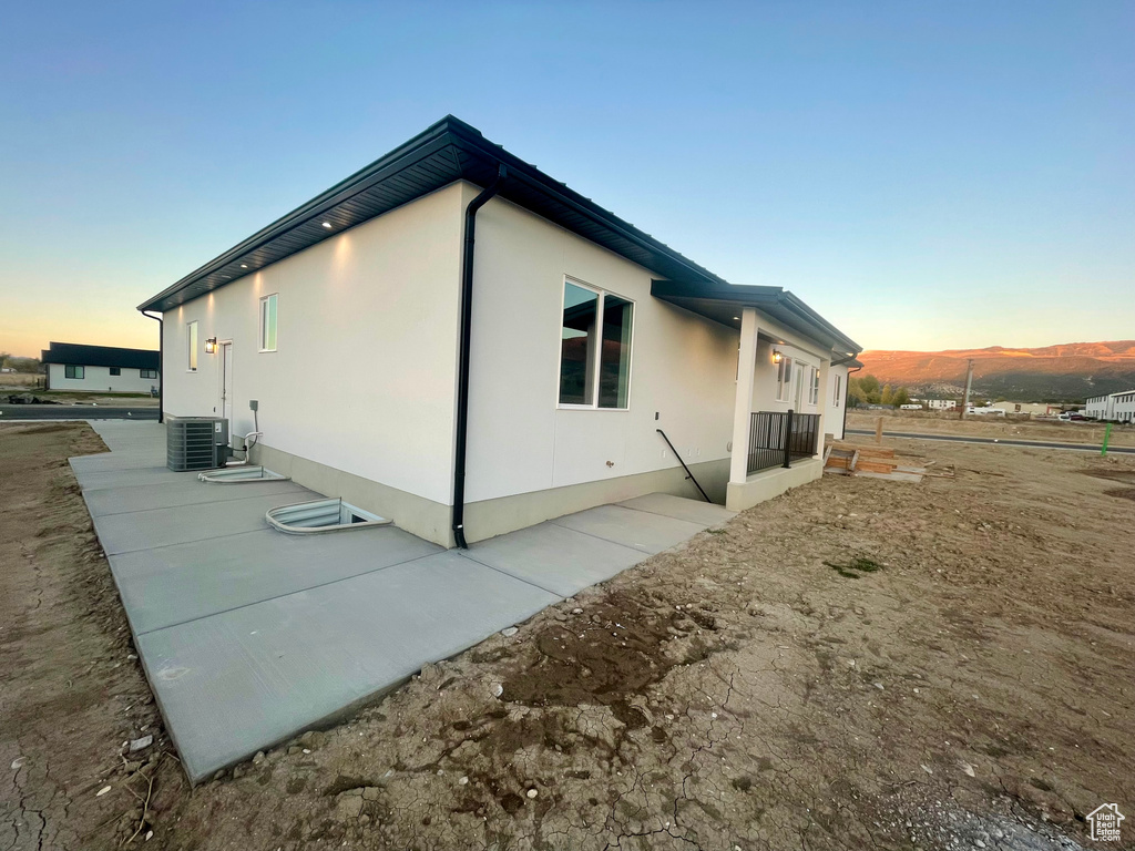 Property exterior at dusk featuring central air condition unit and a patio area