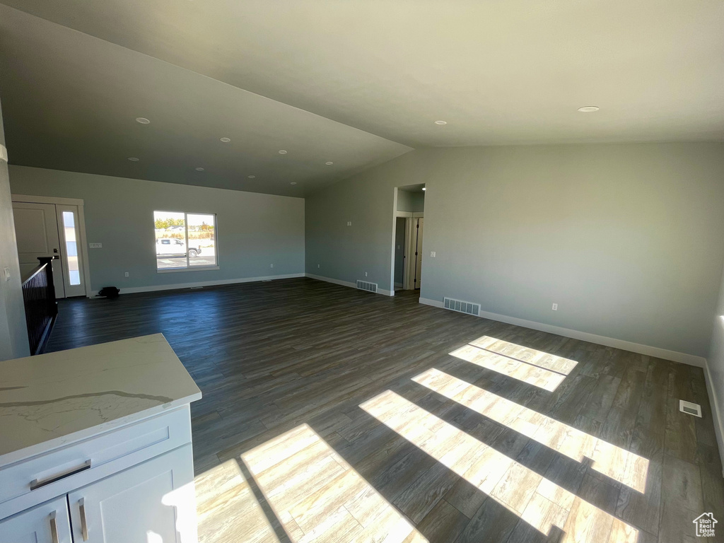 Unfurnished living room with dark wood-type flooring and vaulted ceiling