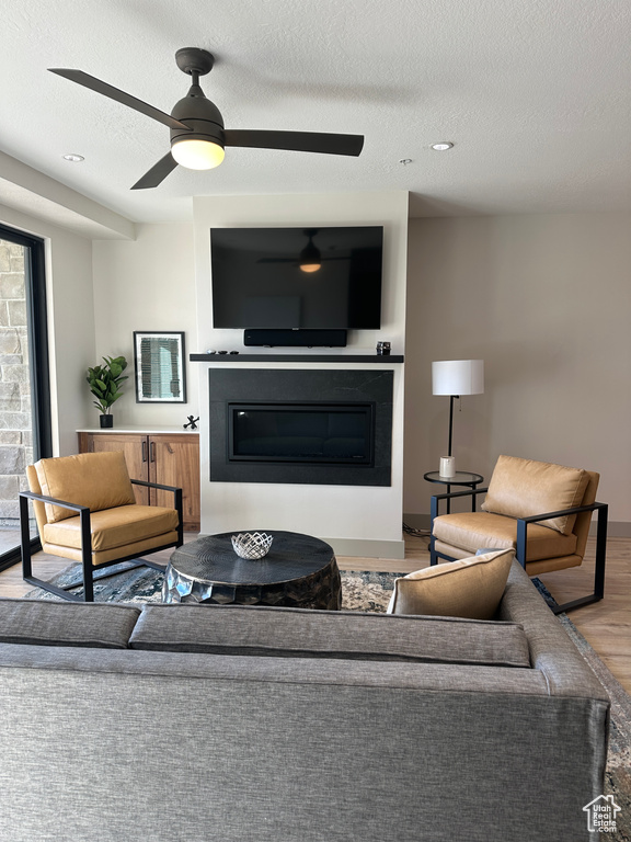 Living room with a textured ceiling, hardwood / wood-style flooring, and ceiling fan