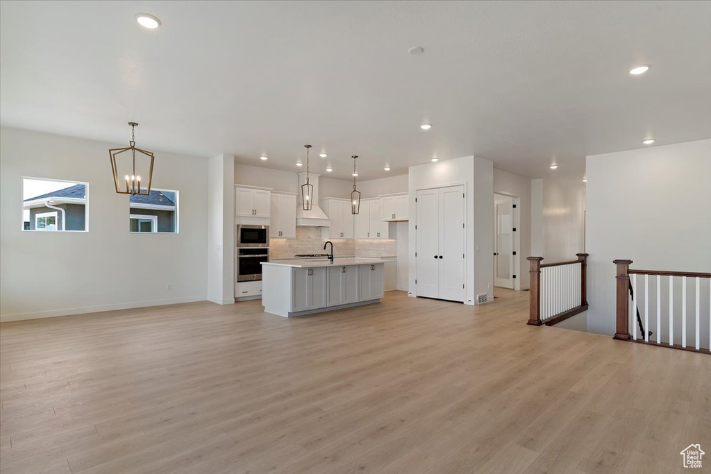 Unfurnished living room featuring a chandelier and light wood-type flooring