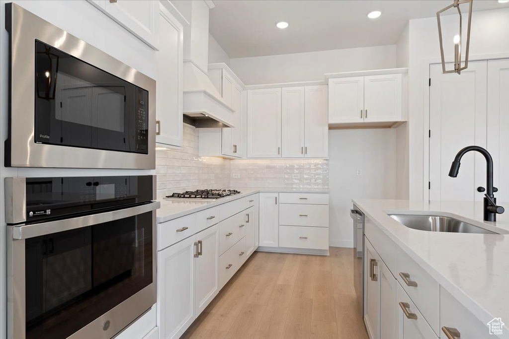 Kitchen featuring sink, white cabinetry, stainless steel appliances, and light wood-type flooring