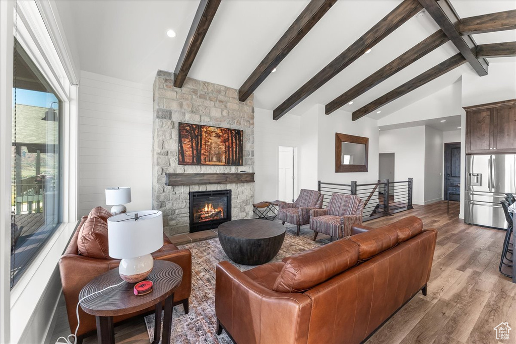 Living room featuring light hardwood / wood-style flooring, vaulted ceiling with beams, and a fireplace