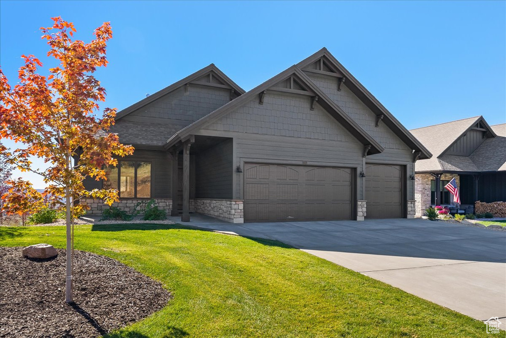 Craftsman inspired home featuring a front lawn and a garage