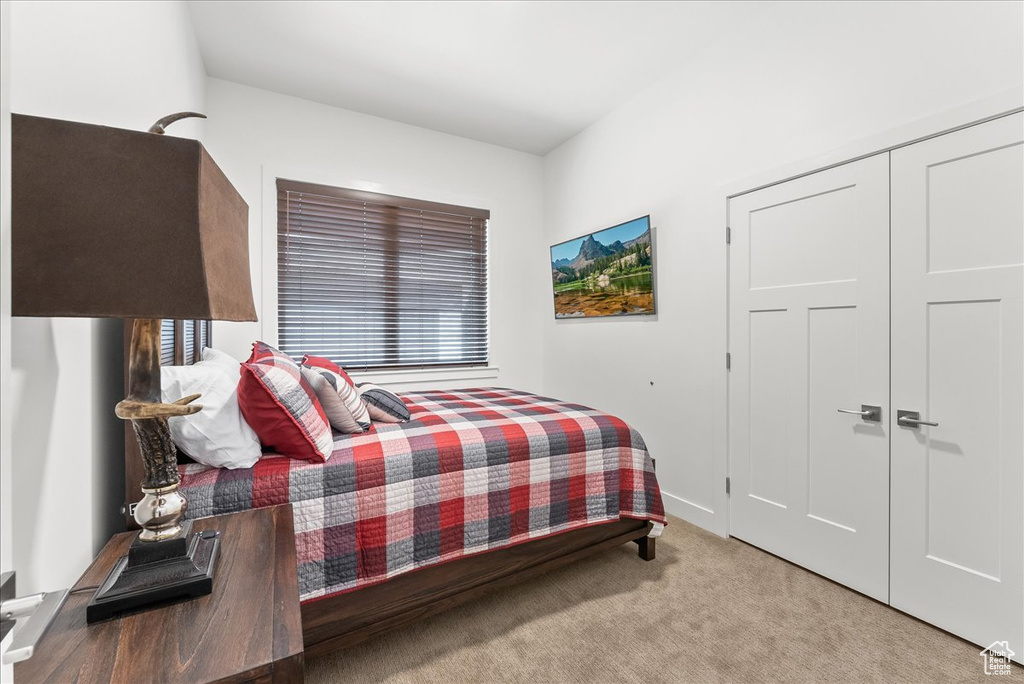 Bedroom with light carpet and a closet