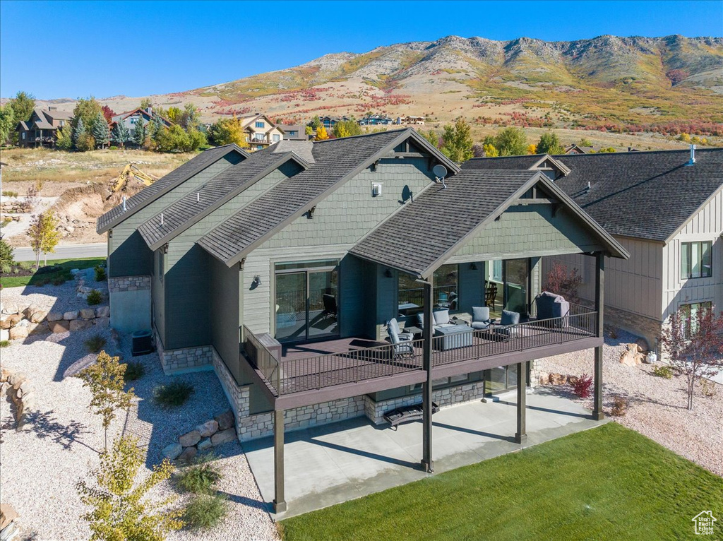 Rear view of house featuring an outdoor living space, a mountain view, and a patio area