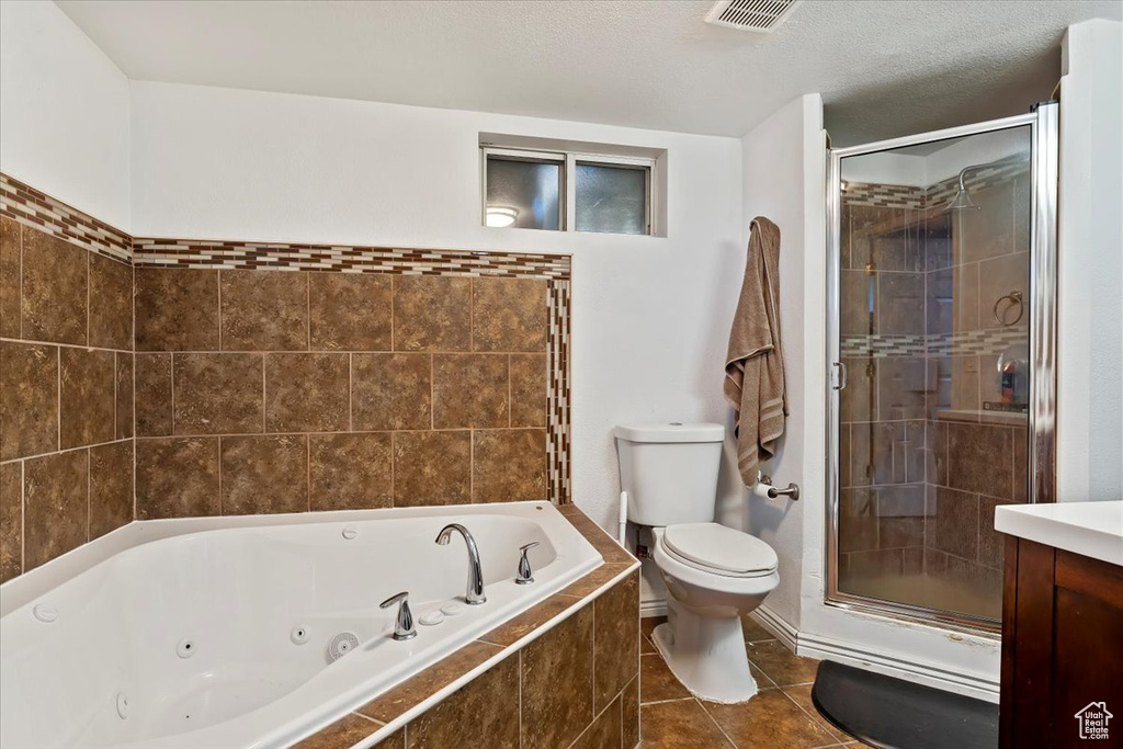 Full bathroom with toilet, tile patterned flooring, separate shower and tub, vanity, and a textured ceiling