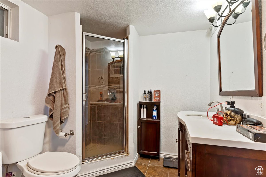 Bathroom featuring a textured ceiling, an enclosed shower, toilet, tile patterned floors, and vanity