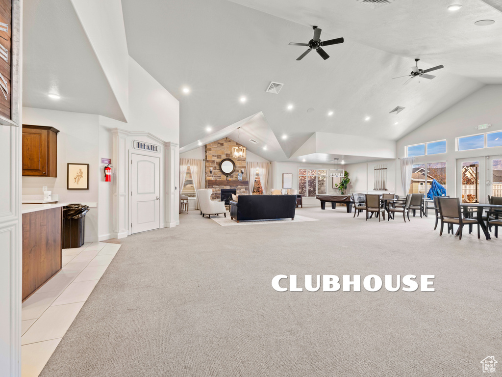 Carpeted living room with ceiling fan, high vaulted ceiling, and a brick fireplace