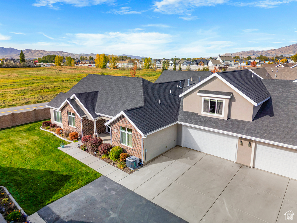 View of front facade with a mountain view, a front yard, cooling unit, and a garage