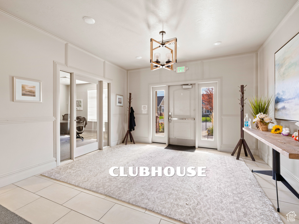 Tiled entryway featuring ornamental molding and a chandelier