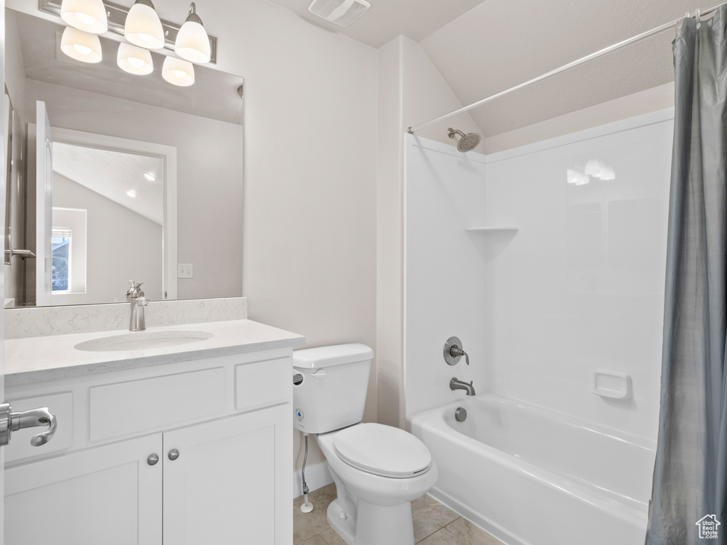 Full bathroom featuring vaulted ceiling, toilet, shower / bath combo, vanity, and tile patterned flooring