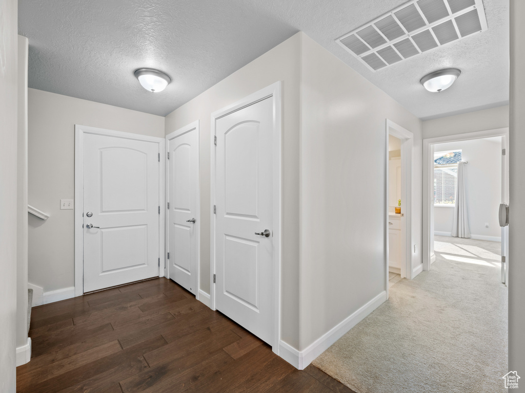 Corridor with dark wood-type flooring and a textured ceiling