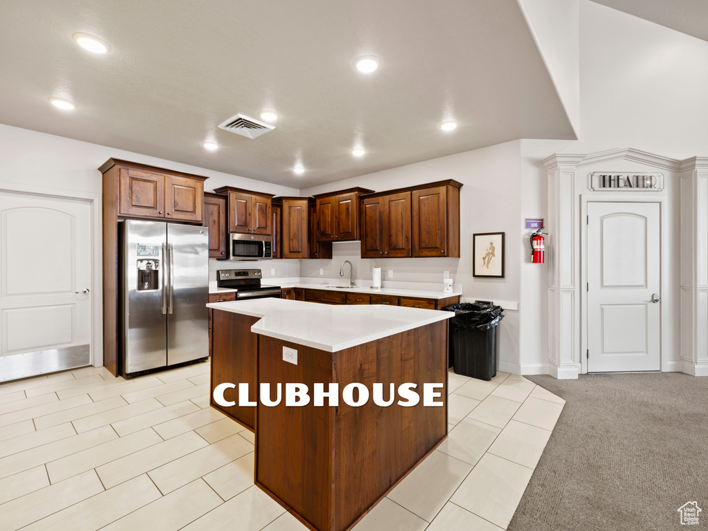 Kitchen with sink, a center island, appliances with stainless steel finishes, and light carpet