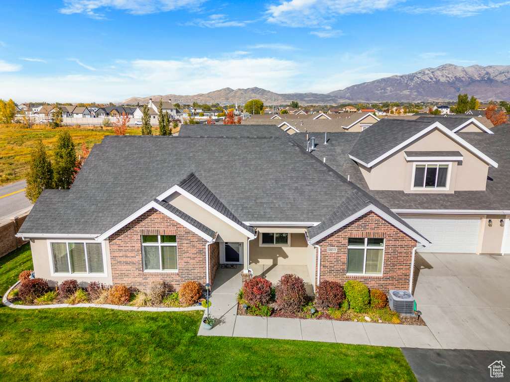 View of front of house featuring a mountain view, a front yard, central AC unit, and a garage