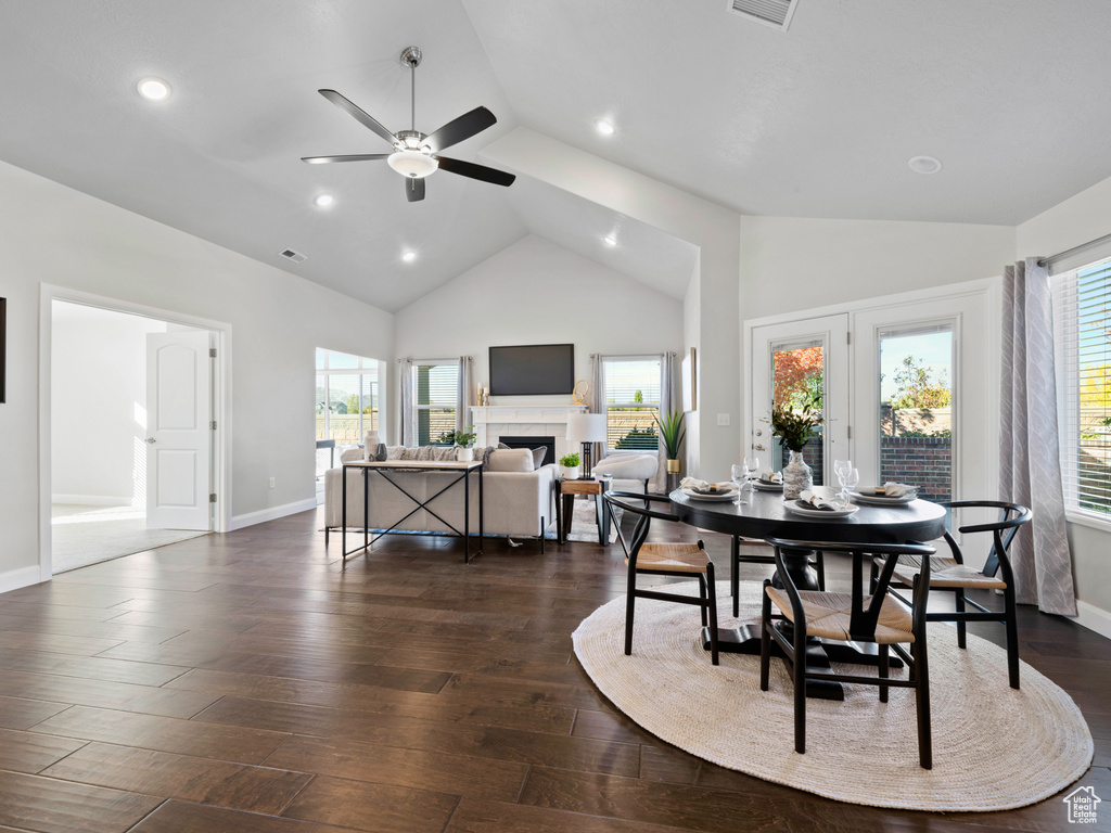 Dining room featuring dark wood-type flooring, ceiling fan, and high vaulted ceiling