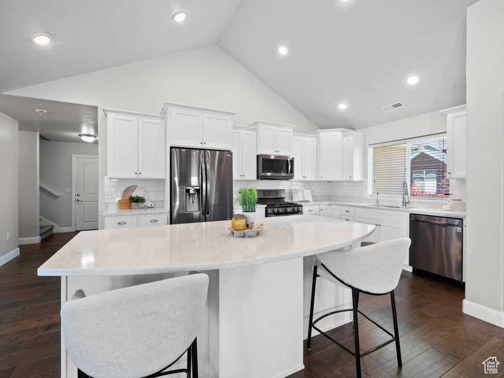 Kitchen featuring appliances with stainless steel finishes, sink, a center island, dark hardwood / wood-style flooring, and white cabinetry