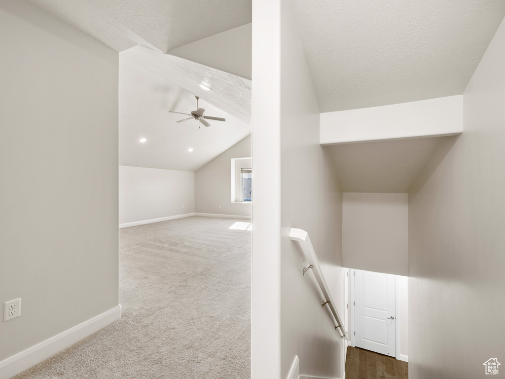 Stairway featuring ceiling fan, carpet flooring, and lofted ceiling