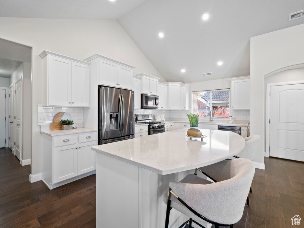 Kitchen featuring dark hardwood / wood-style floors, white cabinetry, stainless steel appliances, and a kitchen island