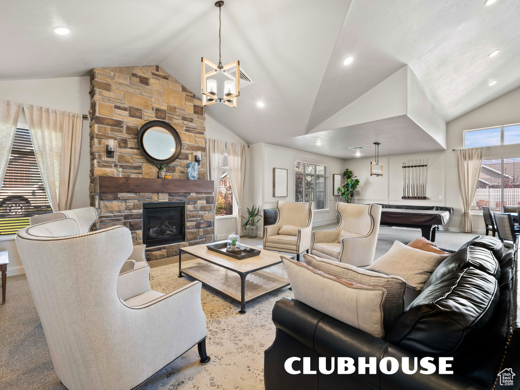 Living room with lofted ceiling, a stone fireplace, light carpet, and a chandelier