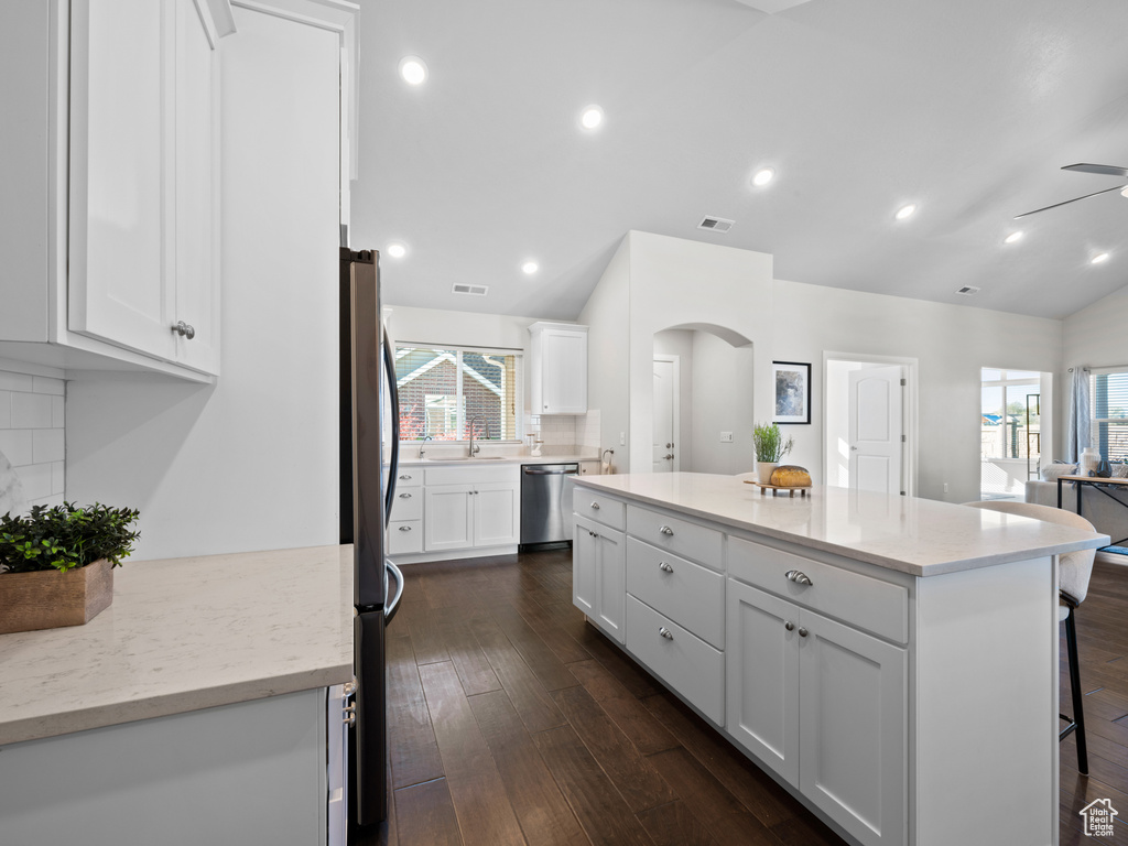 Kitchen featuring a kitchen island, white cabinets, dark hardwood / wood-style flooring, appliances with stainless steel finishes, and tasteful backsplash