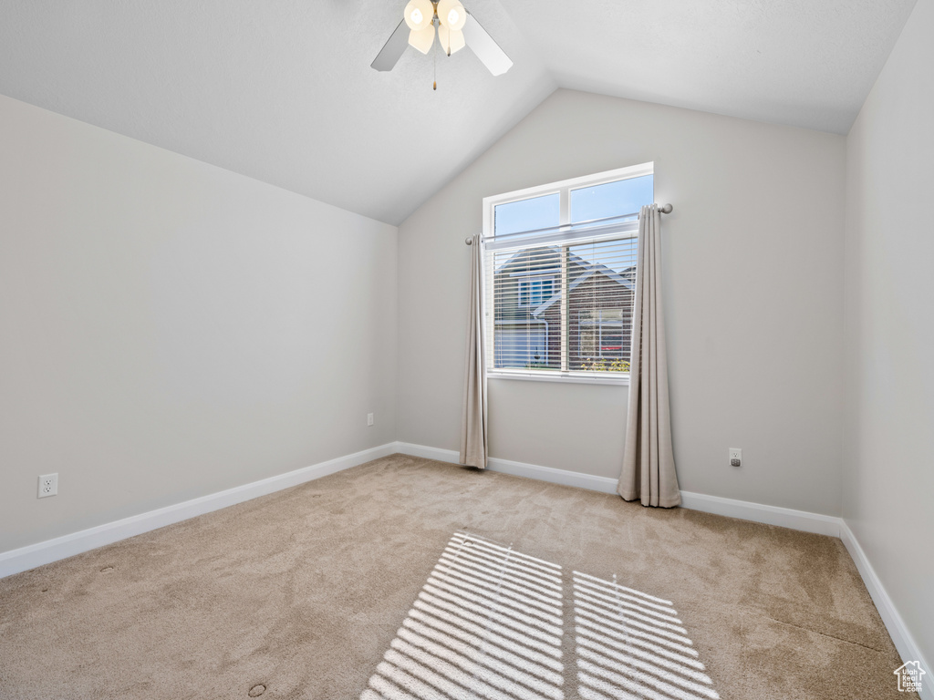 Carpeted empty room with ceiling fan and vaulted ceiling