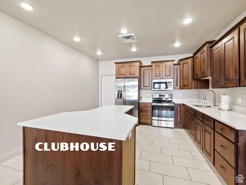 Kitchen with sink, light tile patterned floors, appliances with stainless steel finishes, and a center island