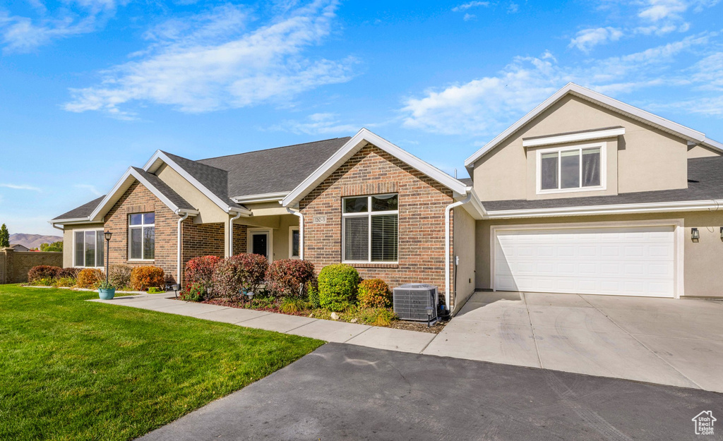 View of front of house featuring central AC, a front lawn, and a garage