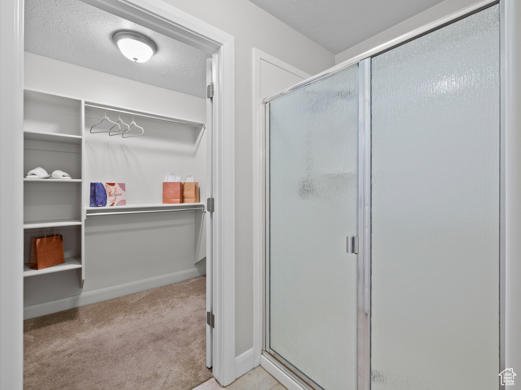 Bathroom featuring a textured ceiling and a shower with shower door