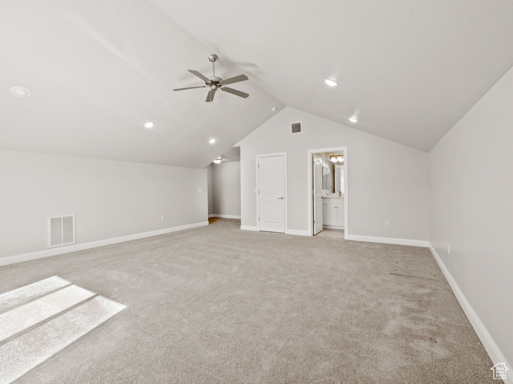 Additional living space featuring ceiling fan, light colored carpet, and vaulted ceiling