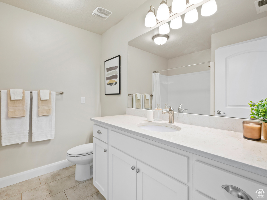 Bathroom featuring vanity, curtained shower, toilet, and tile patterned flooring