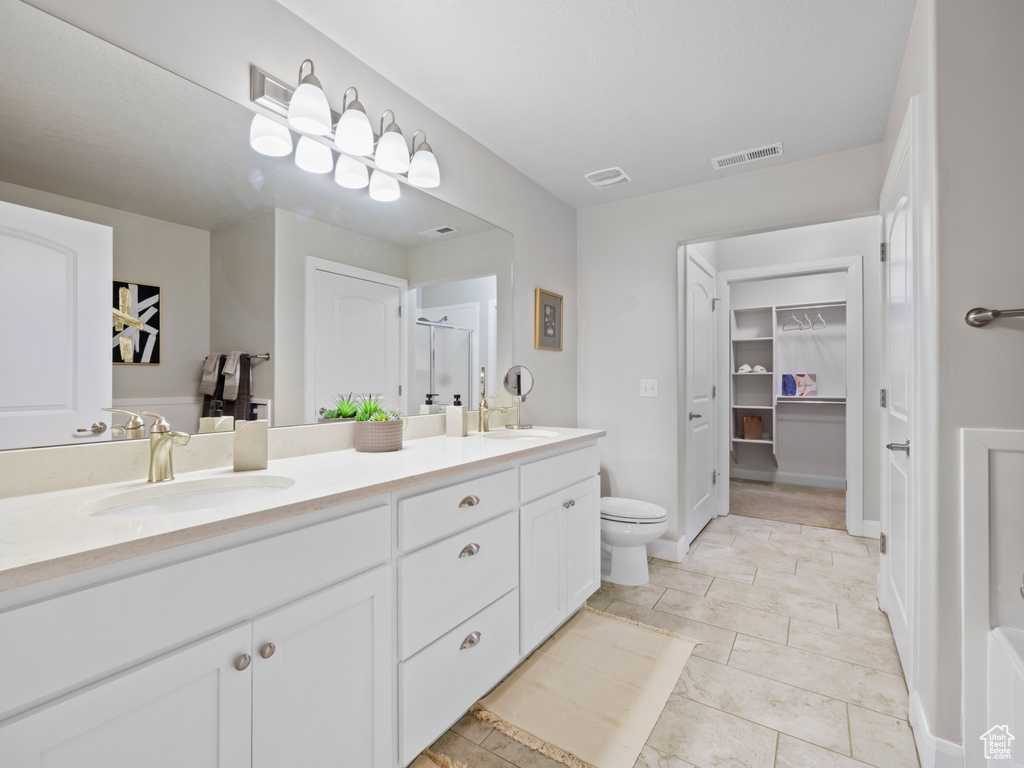 Bathroom with vanity, toilet, tile patterned floors, and walk in shower