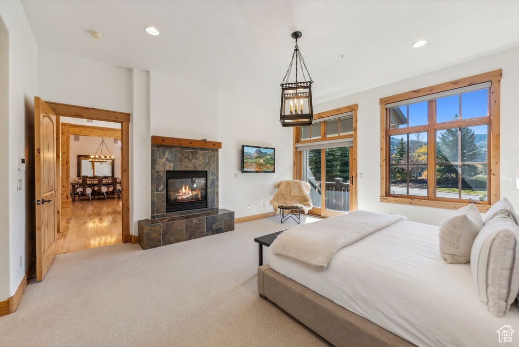 Bedroom featuring a tiled fireplace and light colored carpet