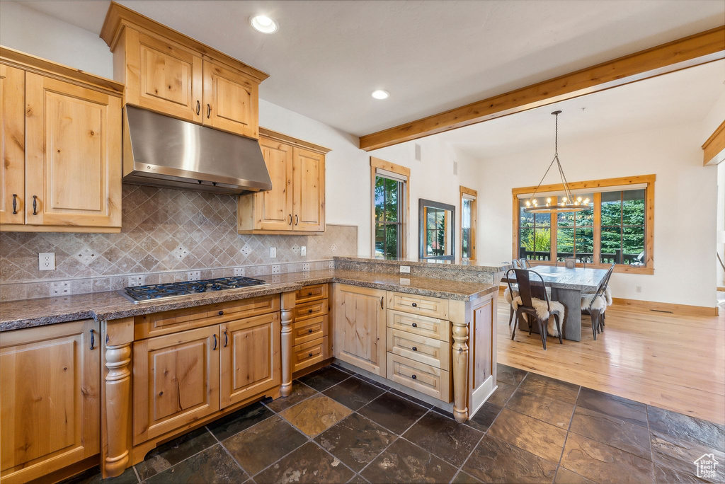 Kitchen with stainless steel gas cooktop, kitchen peninsula, a notable chandelier, and a wealth of natural light