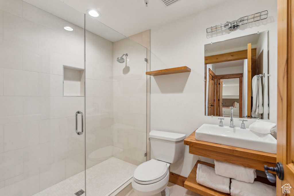 Bathroom featuring vanity, toilet, and an enclosed shower