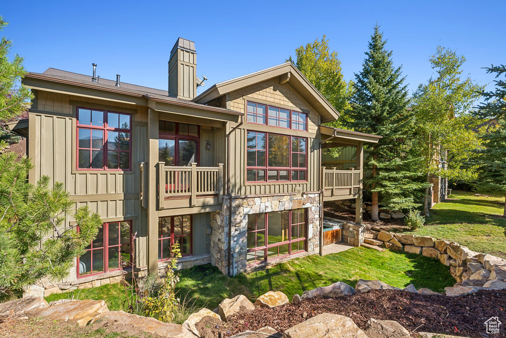 Rear view of property featuring a lawn and a balcony