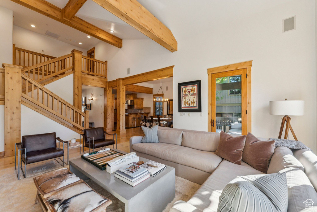 Living room featuring beam ceiling, high vaulted ceiling, and a chandelier