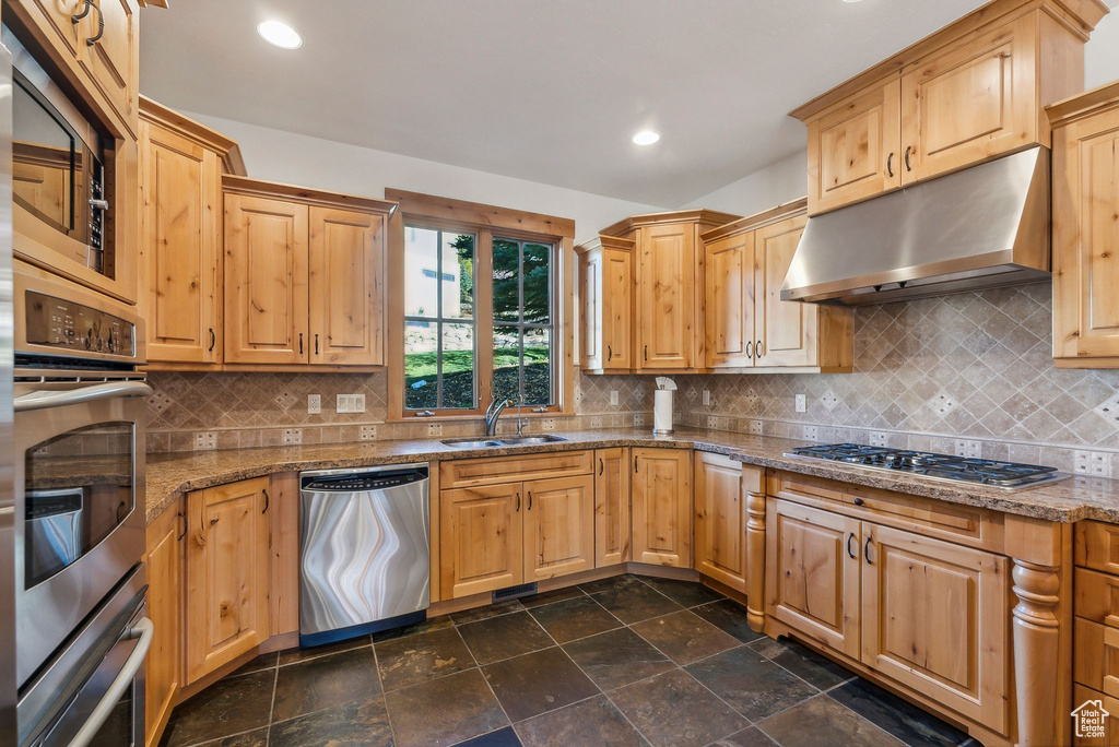 Kitchen featuring stone countertops, tasteful backsplash, appliances with stainless steel finishes, and sink