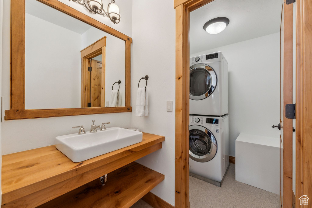 Clothes washing area with light carpet, stacked washing maching and dryer, and sink