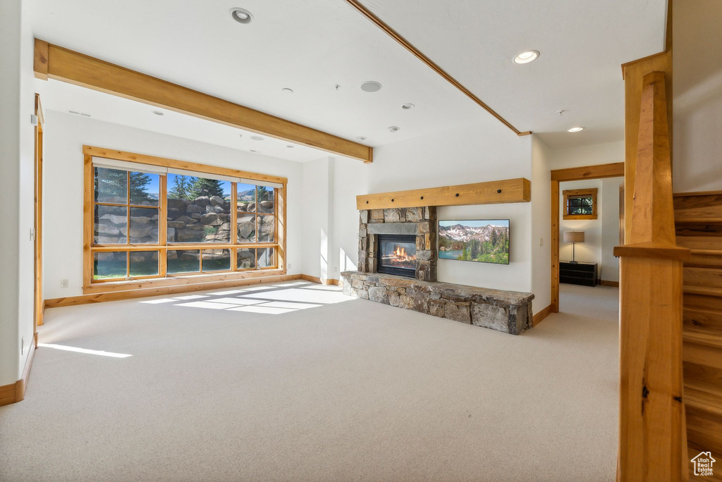 Carpeted living room with beam ceiling and a fireplace