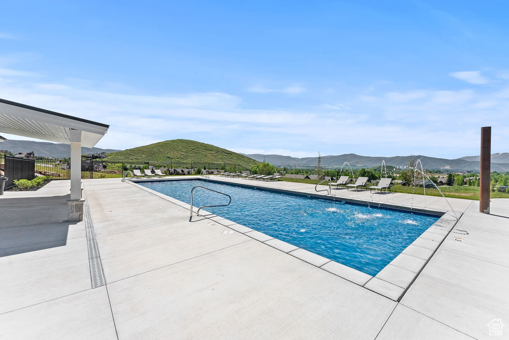 View of pool with a mountain view, pool water feature, and a patio area