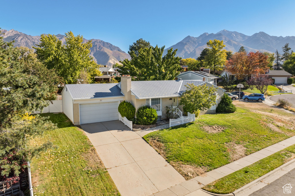 View of front of home with a front yard, a garage, and a mountain view